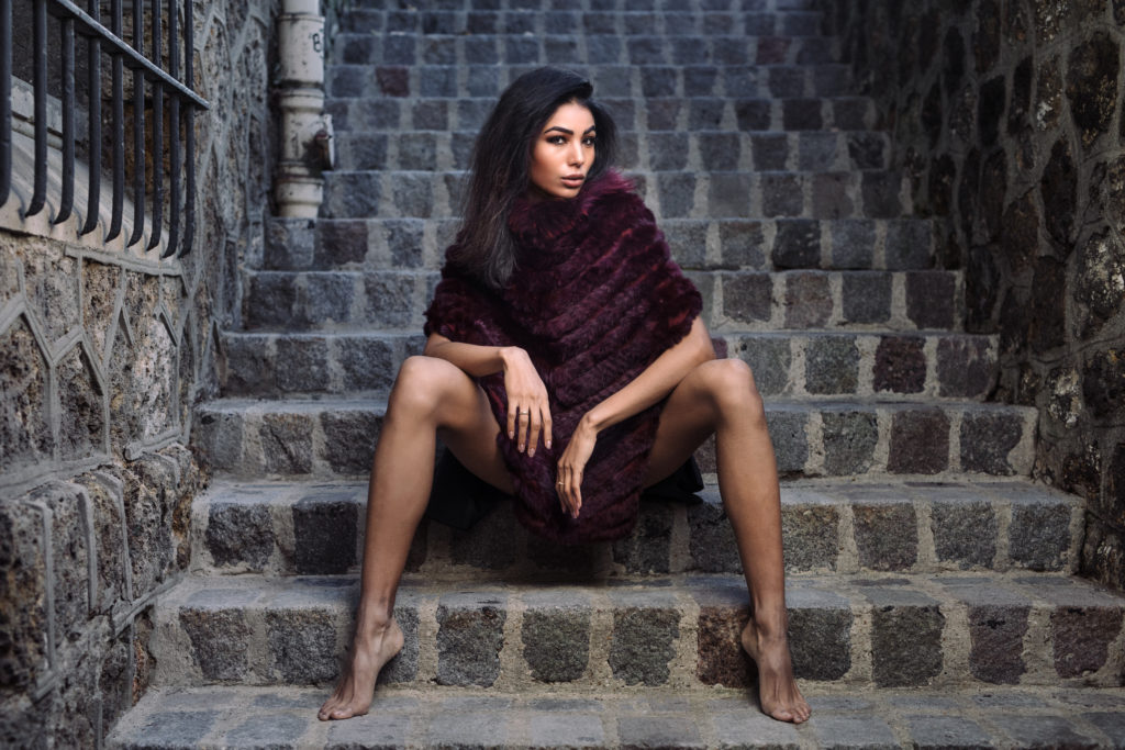 Model wearing fur sitting by stairs in Paris